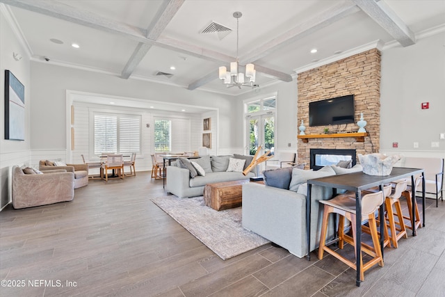 living area featuring visible vents, beamed ceiling, wood finished floors, and a notable chandelier