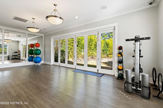 workout area featuring crown molding, baseboards, wood finished floors, and visible vents