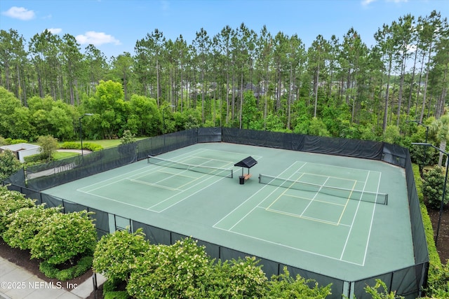 view of sport court with a view of trees and fence