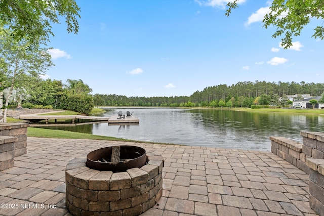 exterior space with a patio, a water view, a fire pit, and a forest view
