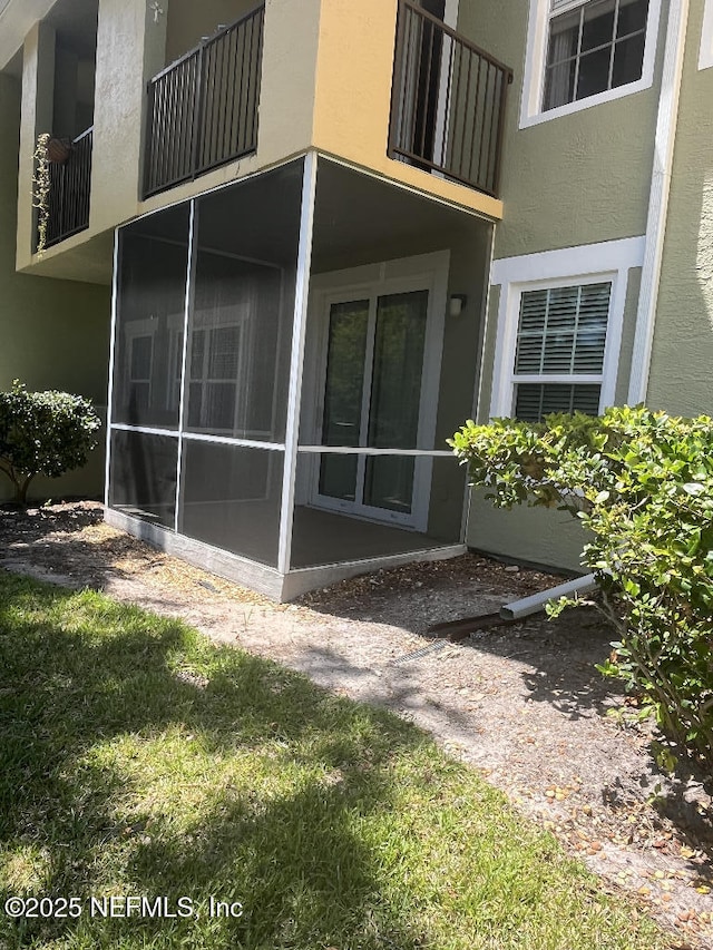 view of home's exterior featuring stucco siding, a sunroom, and a balcony