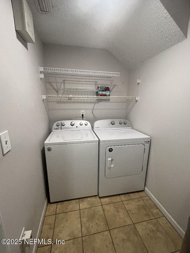 laundry room with washer and dryer, baseboards, tile patterned floors, and a textured ceiling