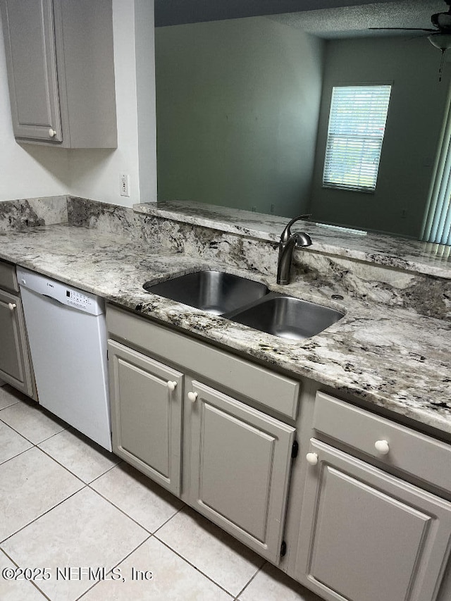 kitchen featuring white dishwasher, a sink, light tile patterned floors, and gray cabinetry