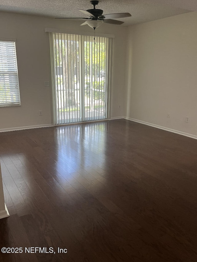 unfurnished room featuring ceiling fan, dark wood-style floors, baseboards, and a textured ceiling