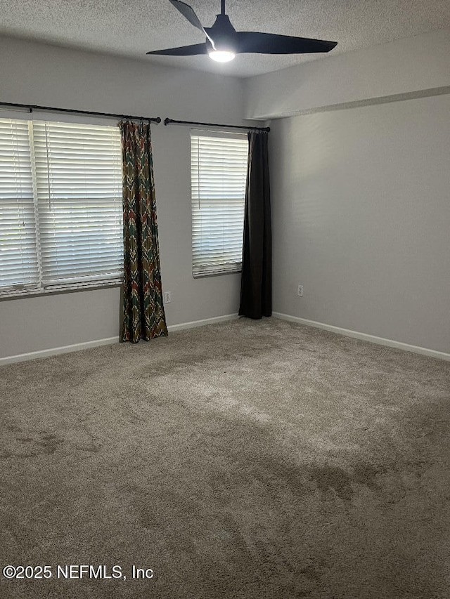 carpeted empty room featuring ceiling fan, a textured ceiling, and baseboards