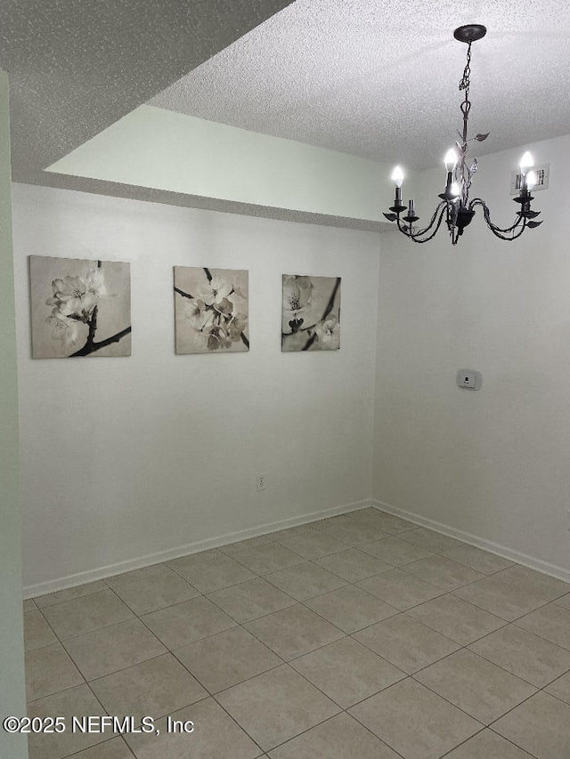 4000 Grande Vista Blvd Unit 15-102, Saint Augustine, FL 32084 - spare room featuring a chandelier, a textured ceiling, light tile patterned flooring, and baseboards