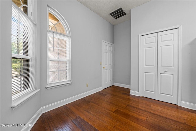 1800 Norway Dr, Fleming Island, FL 32003 - unfurnished bedroom with dark wood-type flooring, multiple windows, baseboards, and a closet