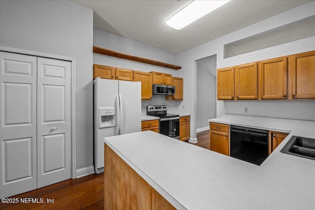 1800 Norway Dr, Fleming Island, FL 32003 - kitchen with stainless steel appliances, dark wood-style floors, baseboards, brown cabinetry, and a textured ceiling