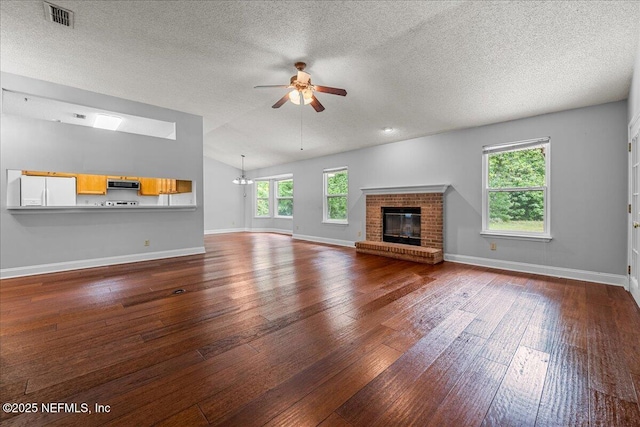 1800 Norway Dr, Fleming Island, FL 32003 - unfurnished living room featuring a ceiling fan, dark wood-style floors, a fireplace, vaulted ceiling, and a textured ceiling