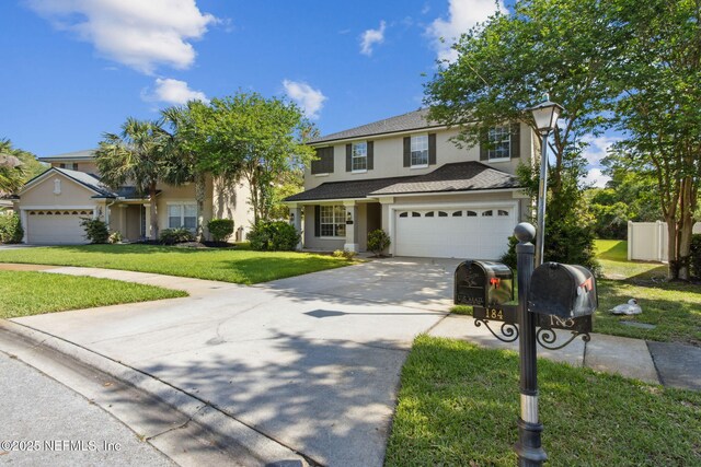 traditional-style house featuring a garage, a front lawn, stucco siding, and driveway