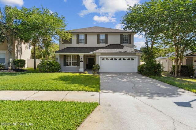 traditional-style house featuring a garage, fence, a front lawn, concrete driveway, and stucco siding
