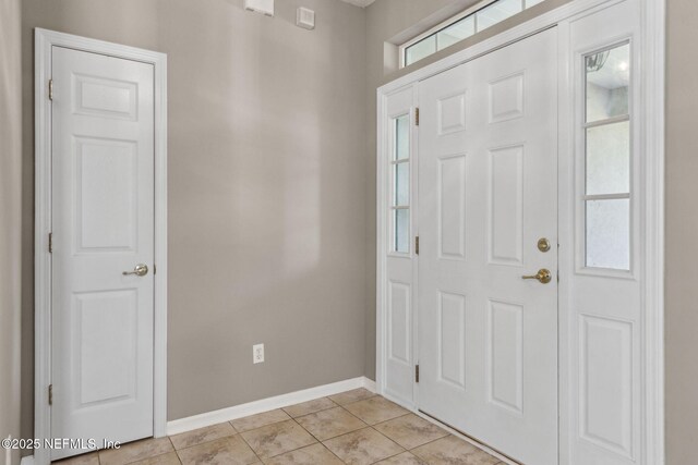 foyer entrance featuring baseboards and light tile patterned floors