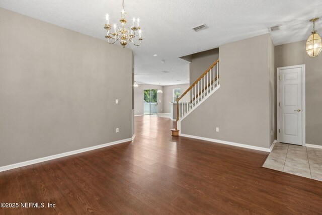 interior space with a notable chandelier, stairs, baseboards, wood finished floors, and visible vents
