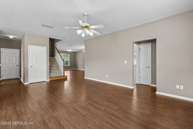 unfurnished living room with ceiling fan, baseboards, wood finished floors, visible vents, and stairway