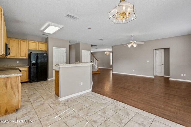 kitchen with visible vents, light countertops, light tile patterned floors, black appliances, and ceiling fan with notable chandelier