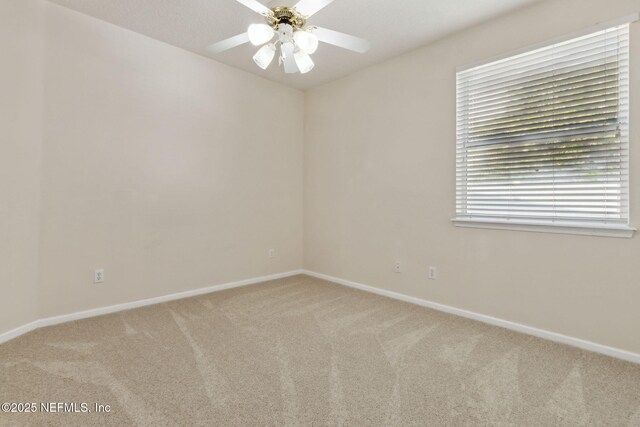carpeted empty room featuring baseboards and ceiling fan