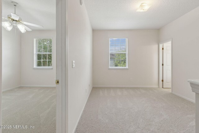 carpeted empty room featuring baseboards, a textured ceiling, and ceiling fan