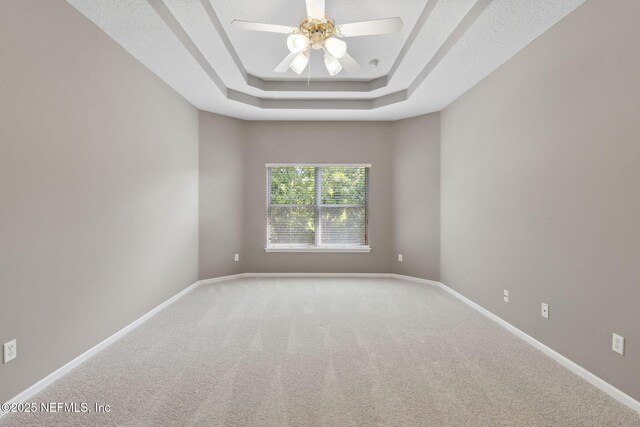 spare room with baseboards, carpet flooring, a raised ceiling, and a ceiling fan