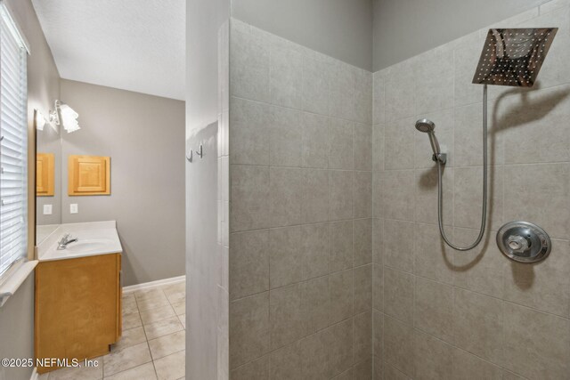 full bathroom featuring a tile shower, a healthy amount of sunlight, tile patterned flooring, and vanity