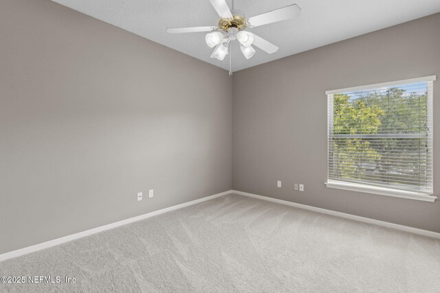 carpeted spare room featuring baseboards and ceiling fan