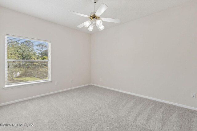 carpeted spare room with baseboards and ceiling fan