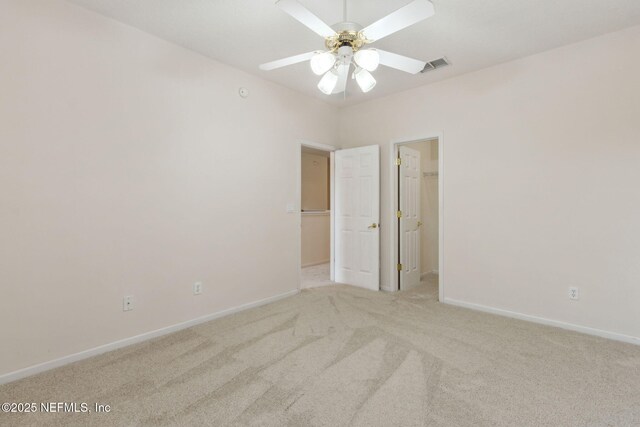 interior space with baseboards, ceiling fan, light carpet, and visible vents