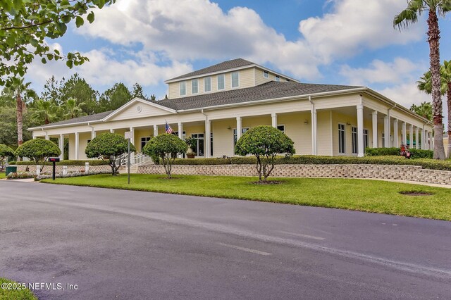 country-style home featuring covered porch and a front yard
