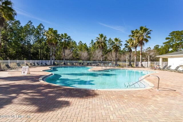 community pool with fence and a patio area