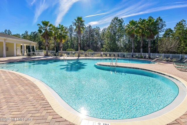 community pool with a patio and fence