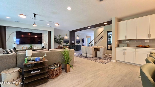 living area featuring visible vents, light wood-style floors, stairway, recessed lighting, and a textured ceiling