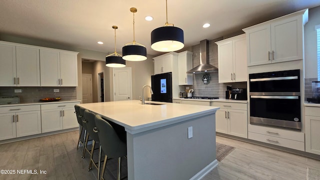 kitchen with wall chimney range hood, backsplash, recessed lighting, and double oven