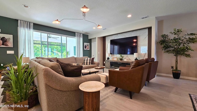 living area featuring a textured ceiling, visible vents, light wood-type flooring, baseboards, and recessed lighting