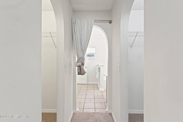 12394 Glenn Hollow Dr, Jacksonville, FL 32226 - hallway with arched walkways, tile patterned floors, carpet flooring, a textured ceiling, and baseboards