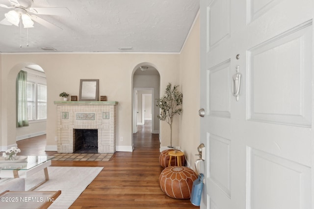 4534 College St, Jacksonville, FL 32205 - living room with arched walkways, a fireplace, wood finished floors, a ceiling fan, and a textured ceiling
