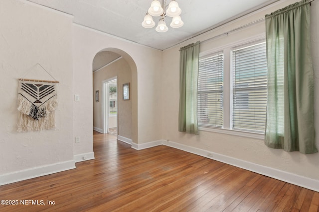 4534 College St, Jacksonville, FL 32205 - unfurnished dining area featuring arched walkways, a chandelier, hardwood / wood-style flooring, and baseboards