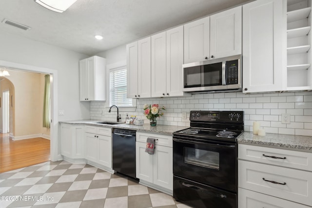 4534 College St, Jacksonville, FL 32205 - kitchen with black appliances, a sink, light flooring, open shelves, and white cabinets