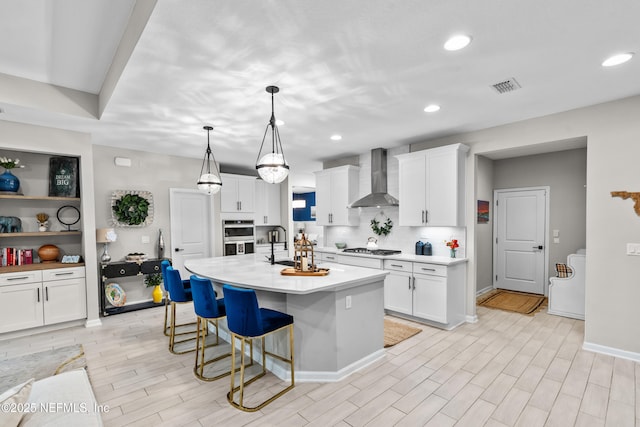 49 Golden Fern Dr, Saint Augustine, FL 32092 - kitchen featuring white cabinets, wall chimney range hood, light countertops, and a breakfast bar