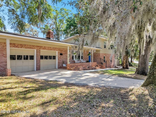 view of front of home with brick siding, a garage, a chimney, and concrete driveway