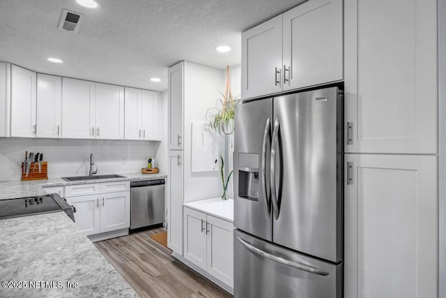 kitchen featuring a sink, light countertops, stainless steel appliances, and white cabinetry