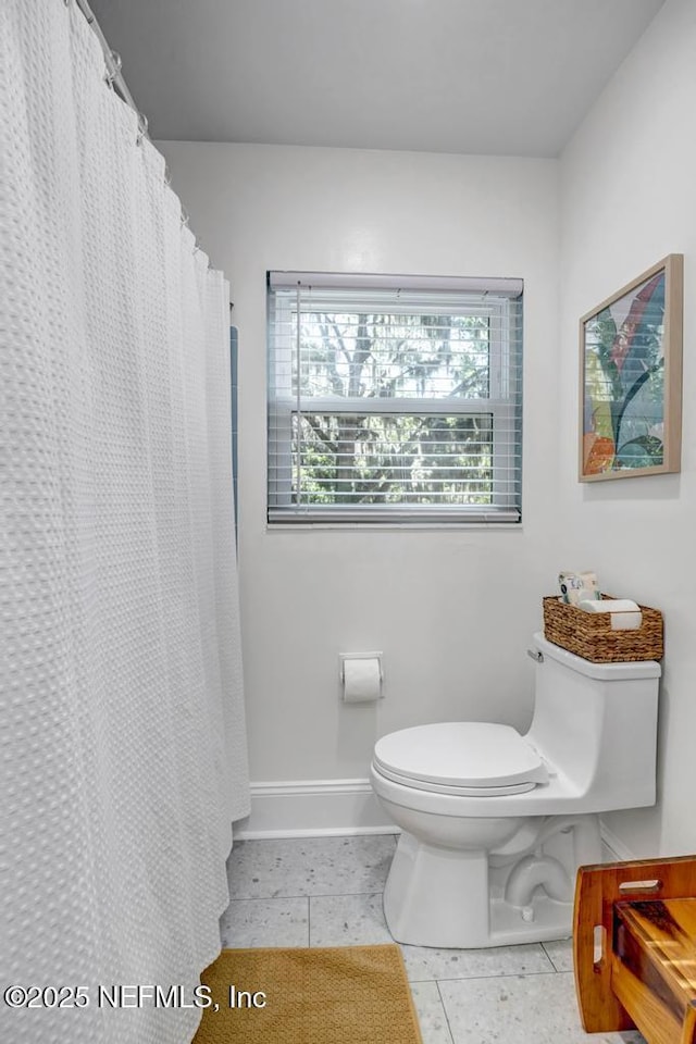 full bathroom featuring baseboards, tile patterned floors, and toilet