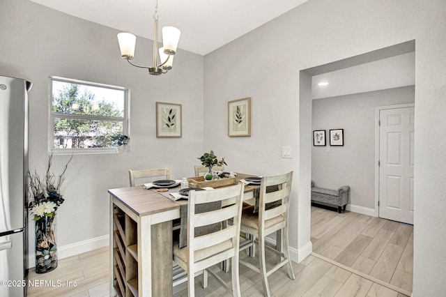 dining room with an inviting chandelier, baseboards, and light wood finished floors