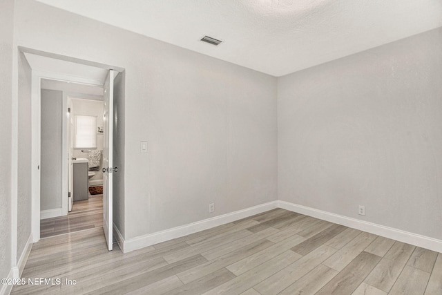 empty room with baseboards, light wood-type flooring, and visible vents