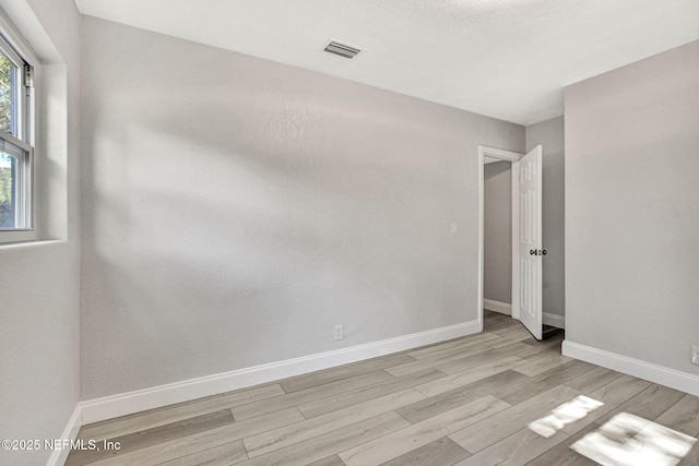 spare room featuring light wood-style floors, baseboards, and visible vents