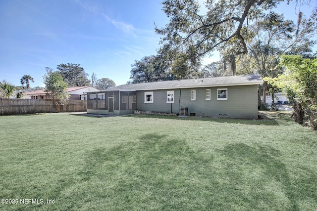 rear view of house featuring a lawn, fence, and a sunroom