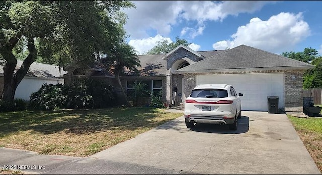 view of front of house with a shingled roof, a front lawn, brick siding, a garage, and driveway