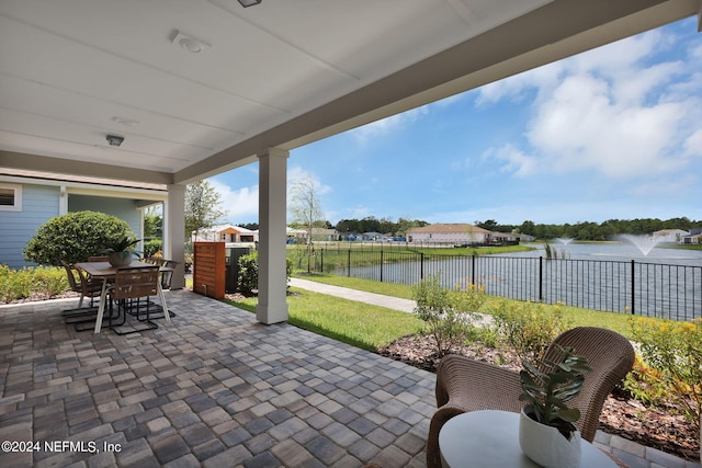 view of patio / terrace featuring fence, outdoor dining space, and a water view