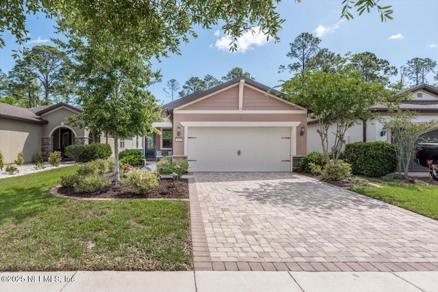 view of front of property featuring stucco siding, decorative driveway, an attached garage, and a front lawn