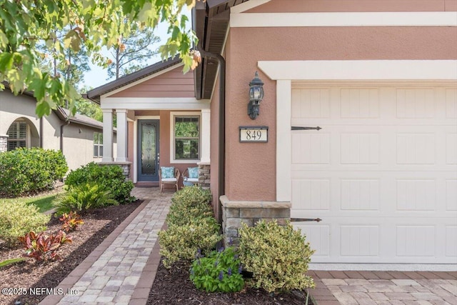 property entrance featuring a garage and stucco siding