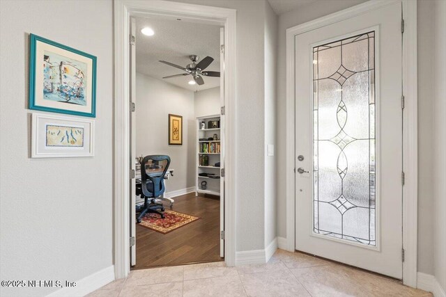 foyer with baseboards, ceiling fan, and light tile patterned floors
