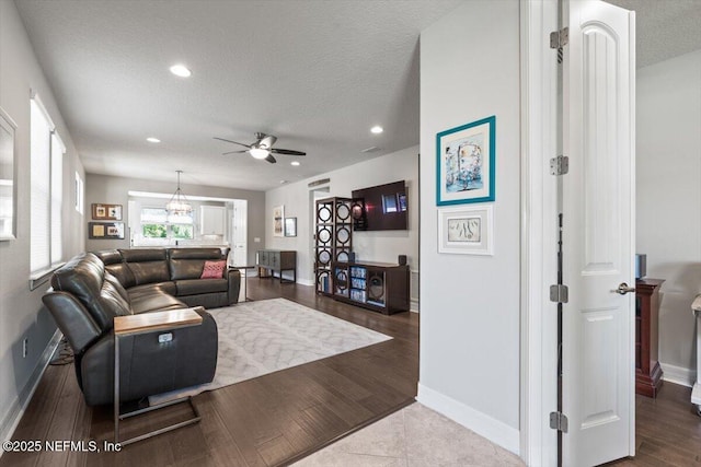 living room featuring baseboards, a ceiling fan, and a textured ceiling